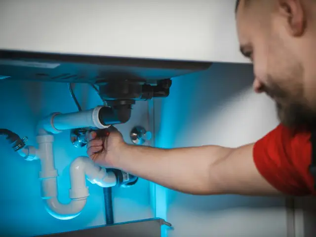 Tesisat ustasının lavabo altındaki boruyu onarması